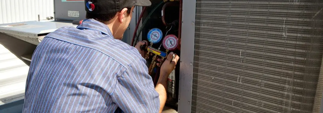 HVAC technician servicing a condenser unit in Signal Hill